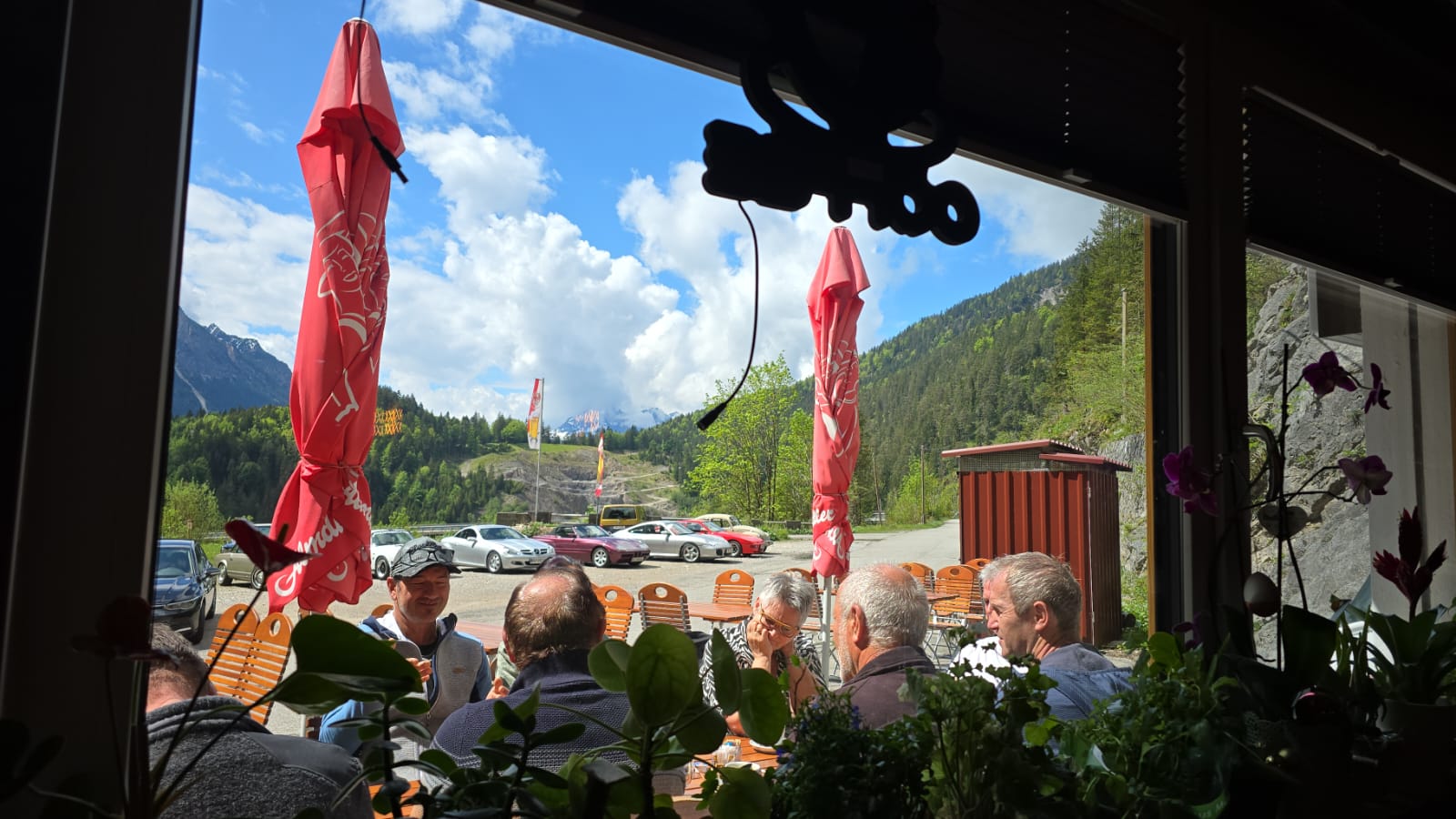 Blick aus dem Gaichtpassstüberl auf die Terrasse mit Oldtimern und Bergpanorama